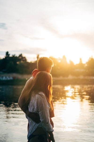 夫妇走在湖边看夕阳特写照片
